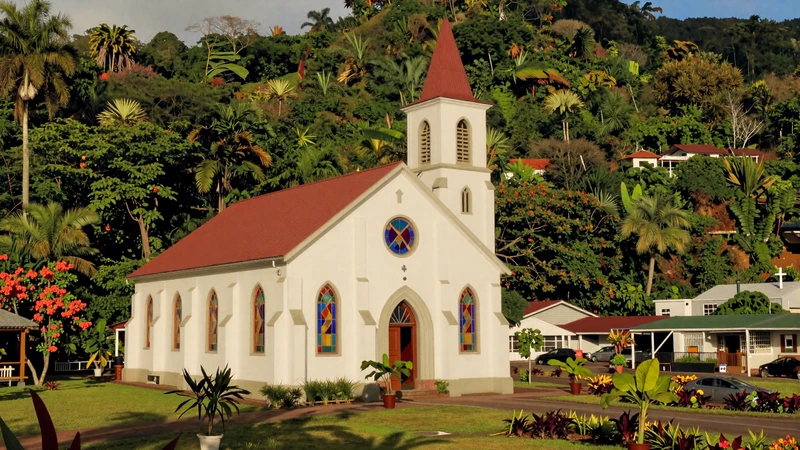 A small Catholic church in Grenada surrounded by lush tropical hillside and flowering gardens